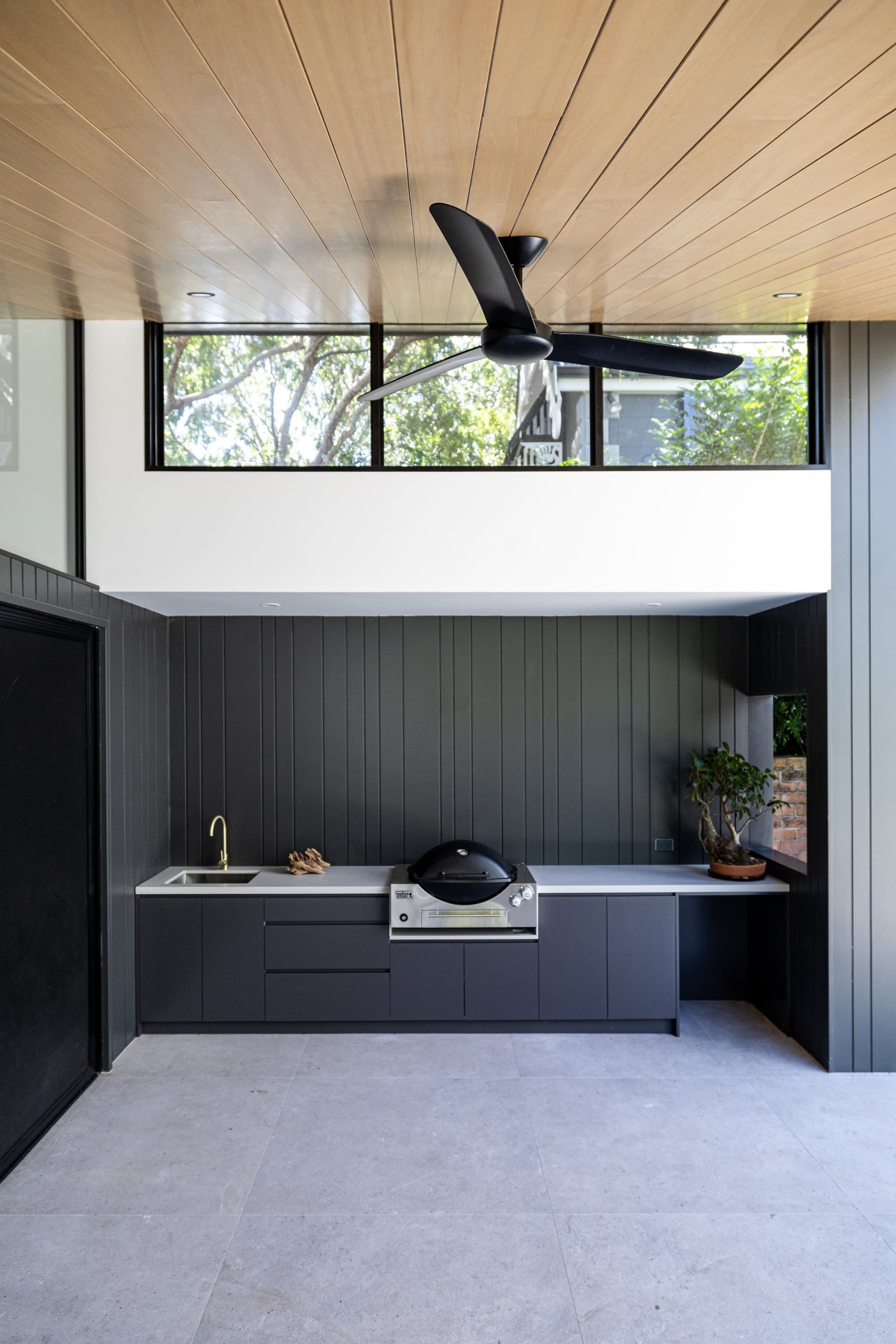 Outdoor kitchen under a timber-lined roof by MBC