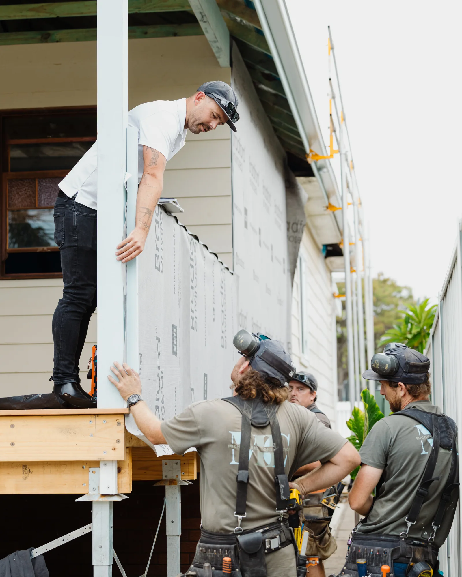 The MBC crew lifting a sheet of cladding into place on a renovation