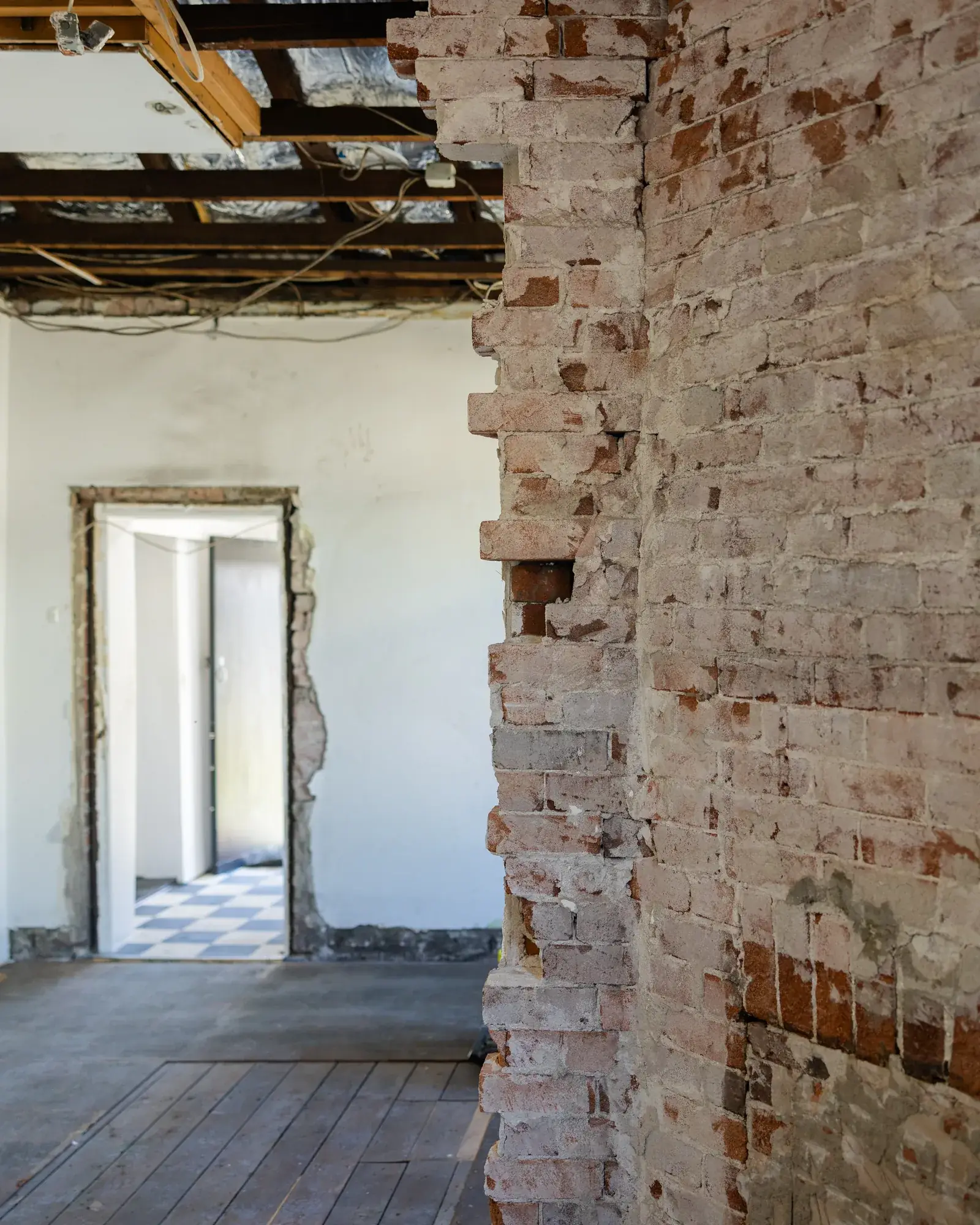Mayfield renovation before — original brick wall exposed with timber structure above
